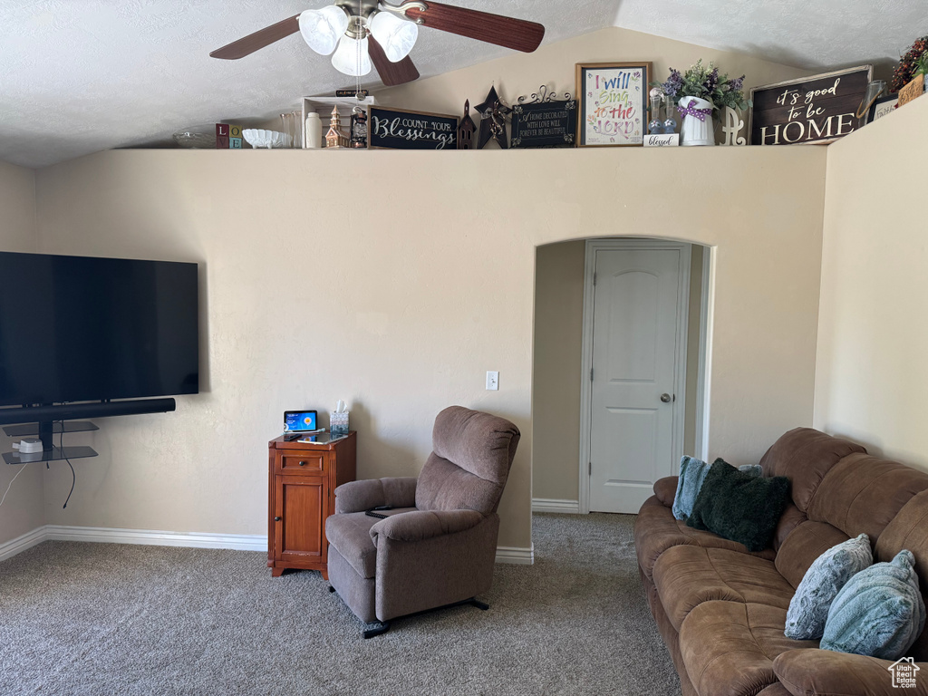 Carpeted living room with ceiling fan, lofted ceiling, a textured ceiling, and baseboards