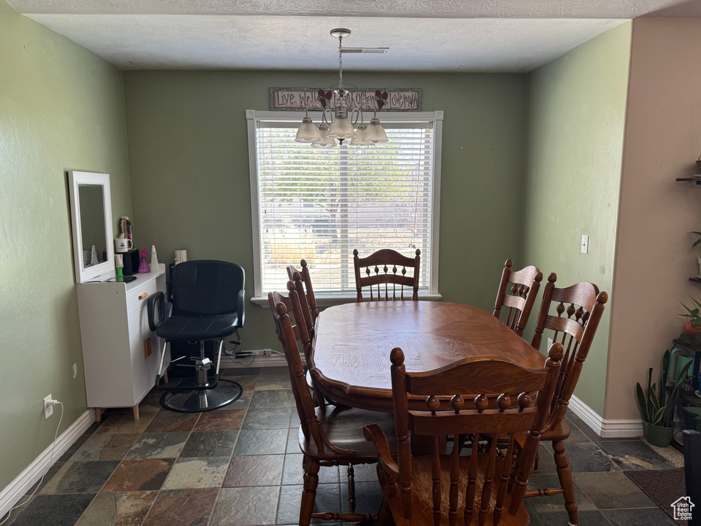 Dining area with stone tile floors, baseboards, an inviting chandelier, and visible vents