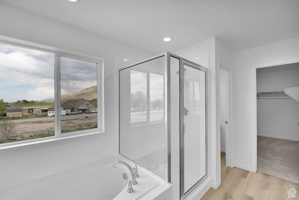 Full bath featuring a stall shower, a bath, wood finished floors, a spacious closet, and recessed lighting