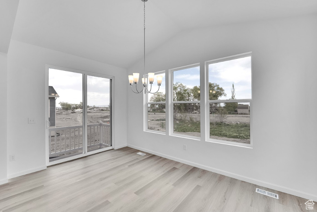Unfurnished dining area featuring a chandelier, wood finished floors, vaulted ceiling, and baseboards
