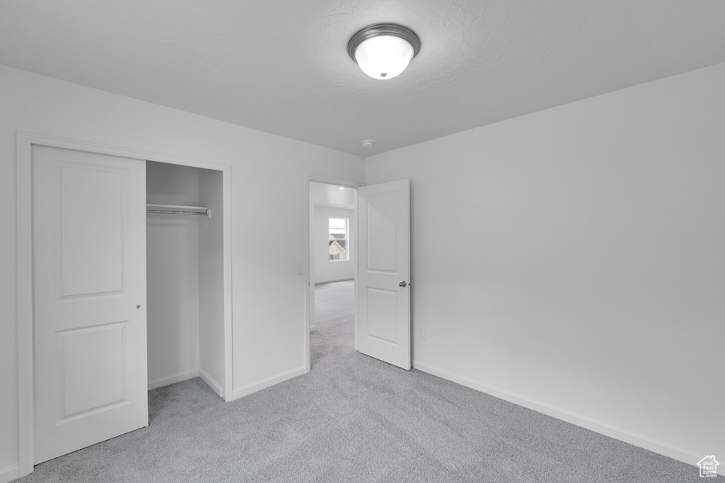 Unfurnished bedroom featuring carpet floors, baseboards, and a closet
