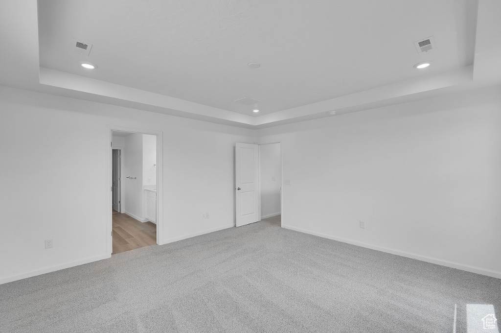Carpeted spare room with a raised ceiling, recessed lighting, and baseboards