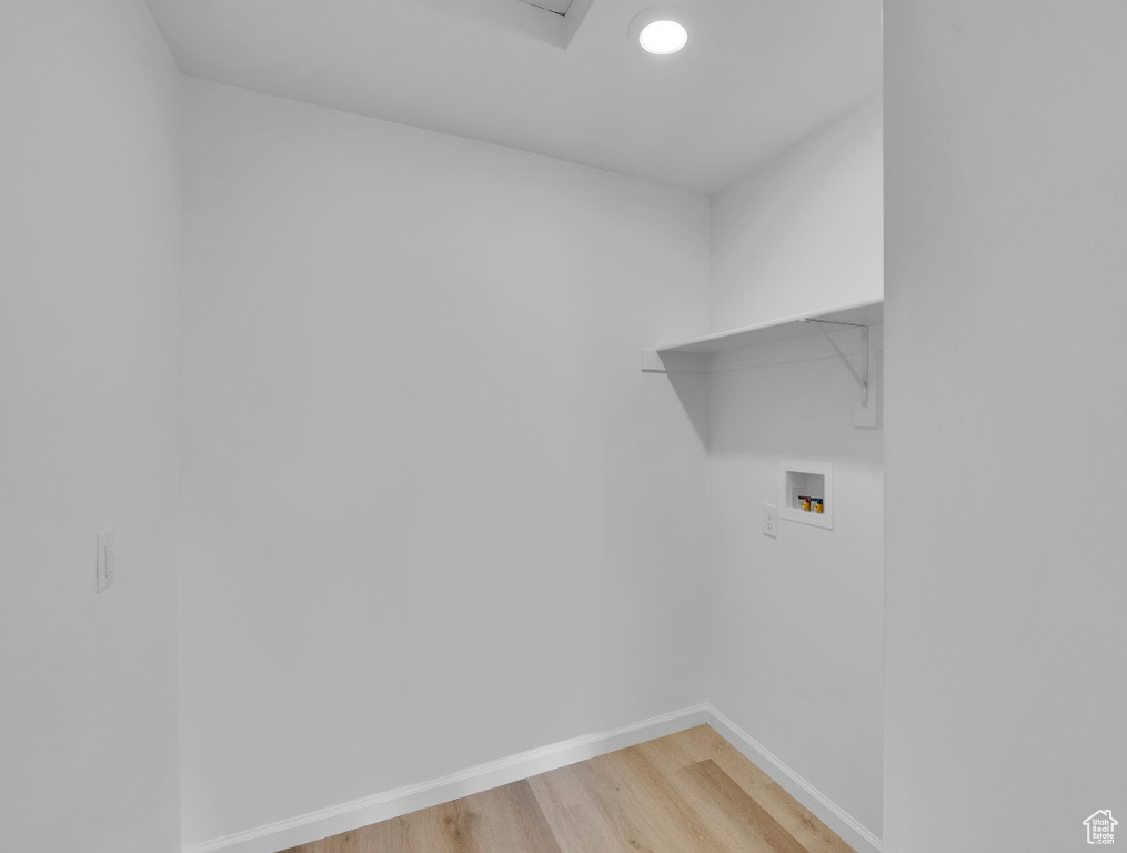 Laundry room with washer hookup, baseboards, and light wood-type flooring