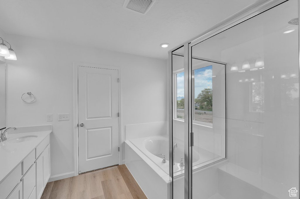 Full bath featuring wood finished floors, a bath, vanity, and a shower stall