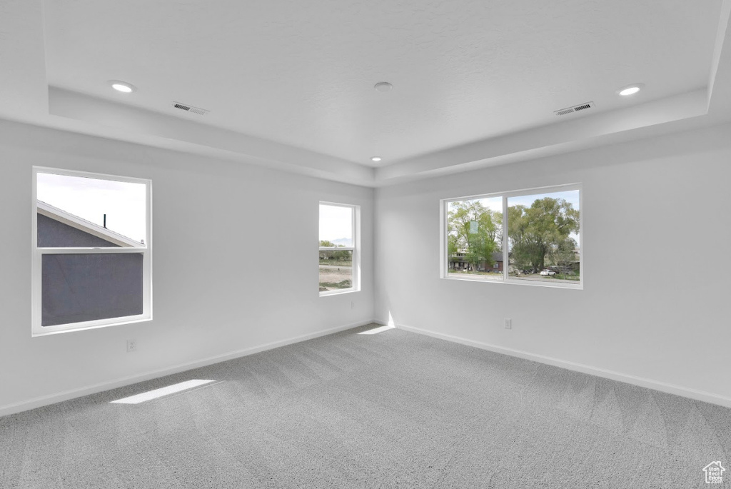 Empty room with a tray ceiling, carpet floors, recessed lighting, and baseboards
