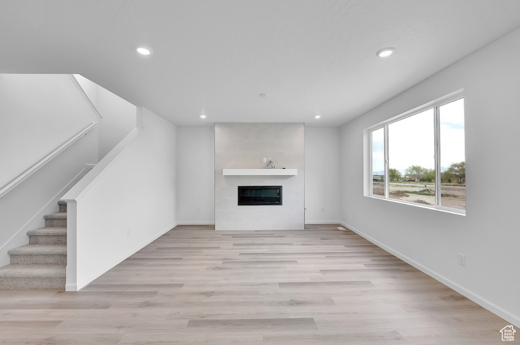 Unfurnished living room with recessed lighting, stairway, baseboards, and a glass covered fireplace