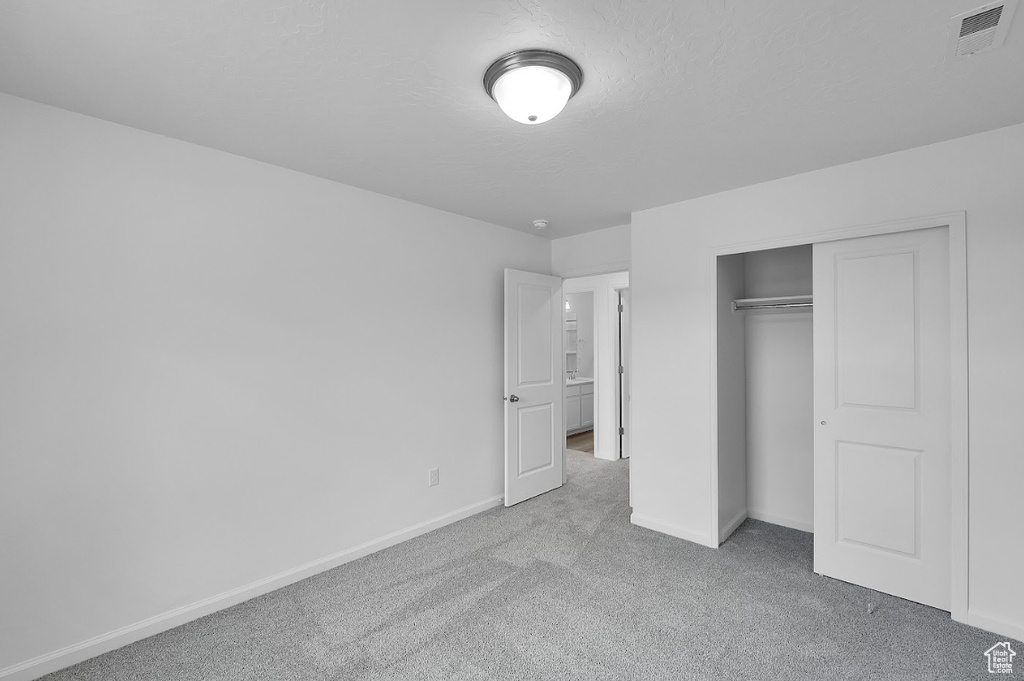 Unfurnished bedroom featuring carpet floors, baseboards, a closet, and a textured ceiling