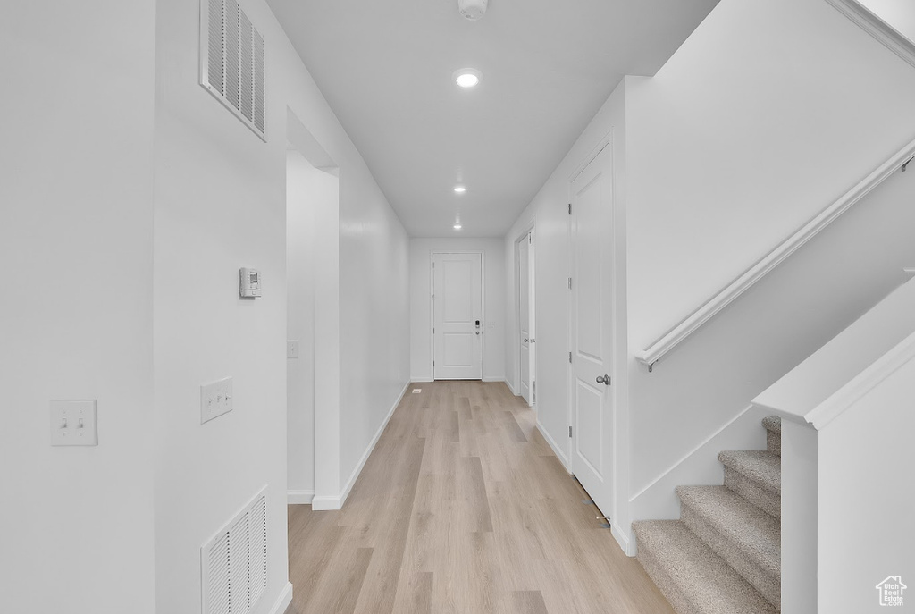 Corridor featuring recessed lighting, light wood finished floors, baseboards, and stairs