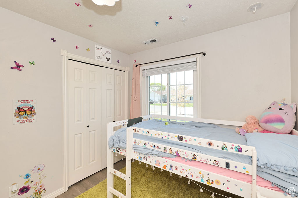 Bedroom with light wood-style flooring, a closet, baseboards, and visible vents