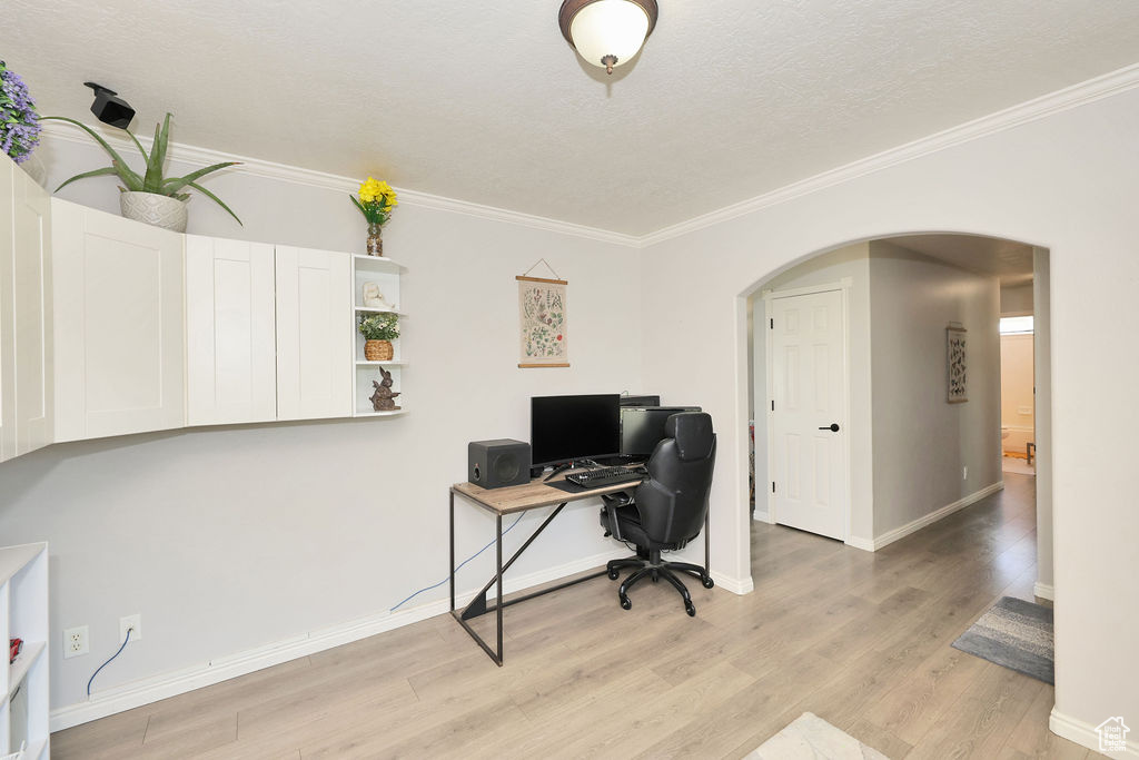 Office featuring arched walkways, light wood-style floors, crown molding, and baseboards
