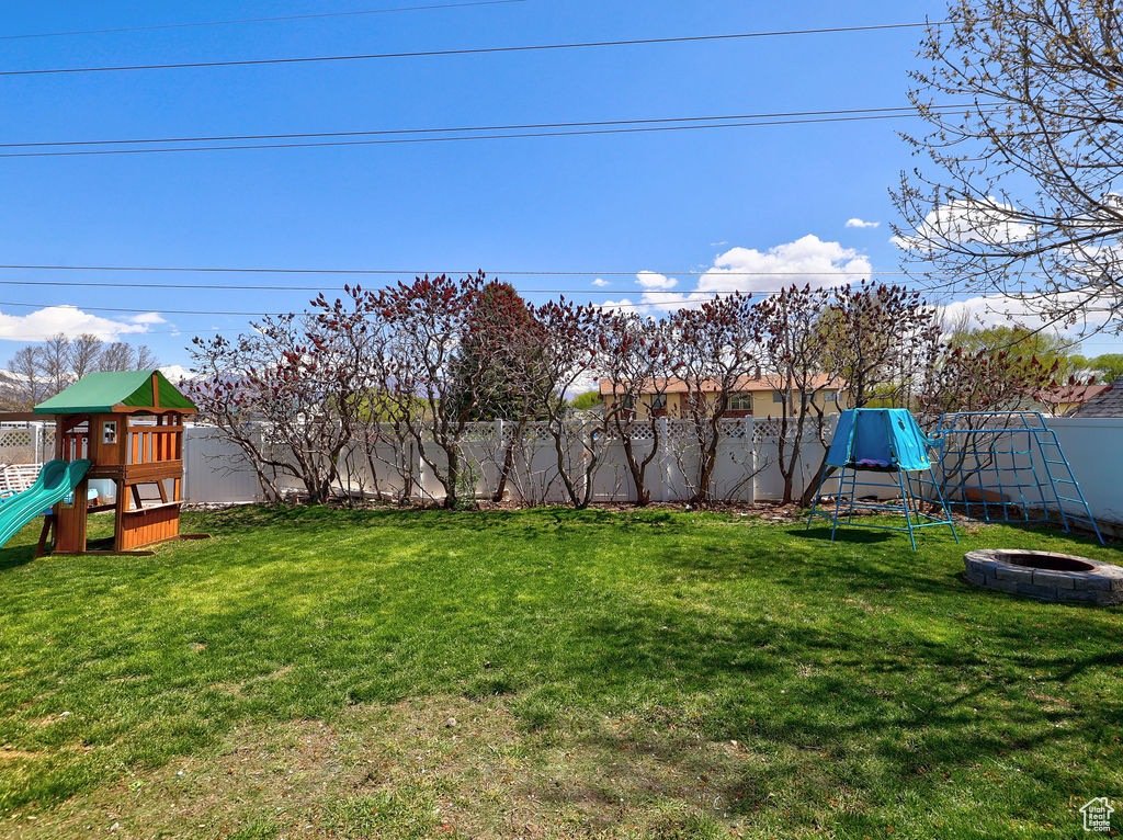 View of yard featuring a fenced backyard, an outdoor fire pit, and a playground