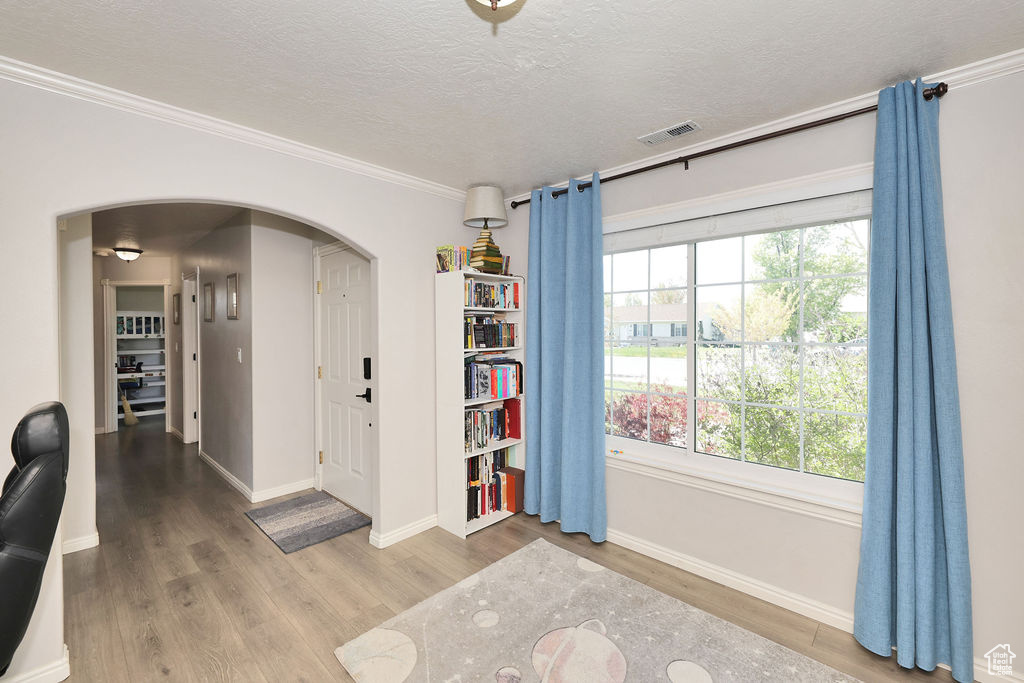 Entrance foyer featuring arched walkways, wood finished floors, visible vents, and a textured ceiling