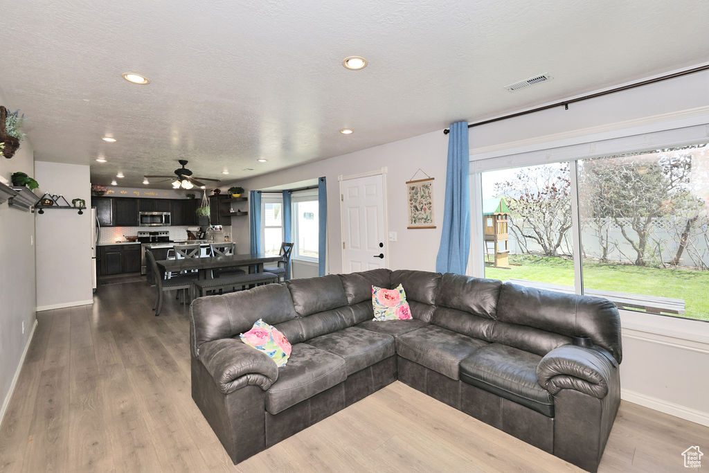 Living room featuring recessed lighting, wood finished floors, visible vents, baseboards, and ceiling fan