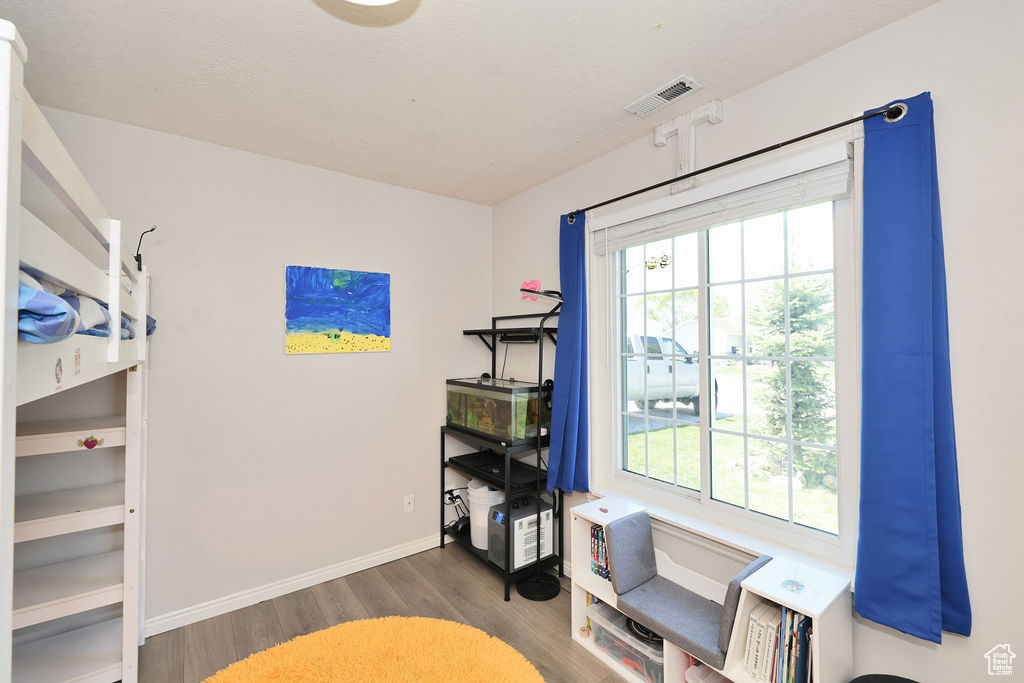 Interior space featuring baseboards, wood finished floors, visible vents, and multiple windows