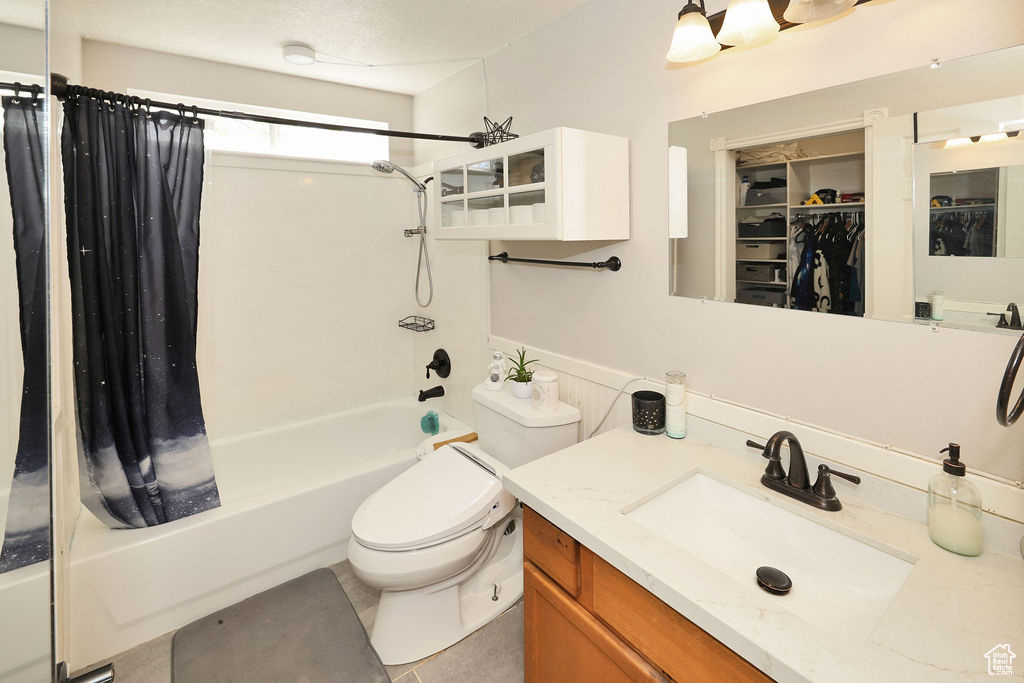 Full bathroom with a spacious closet, toilet, vanity, and shower / bathtub combination with curtain