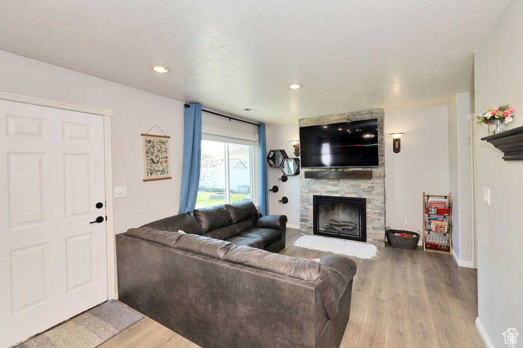 Living area with baseboards, wood finished floors, a fireplace, and recessed lighting