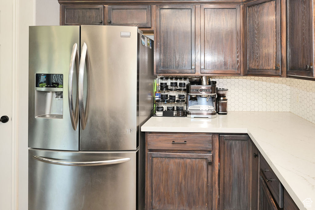 Kitchen featuring dark brown cabinetry, tasteful backsplash, and stainless steel fridge with ice dispenser