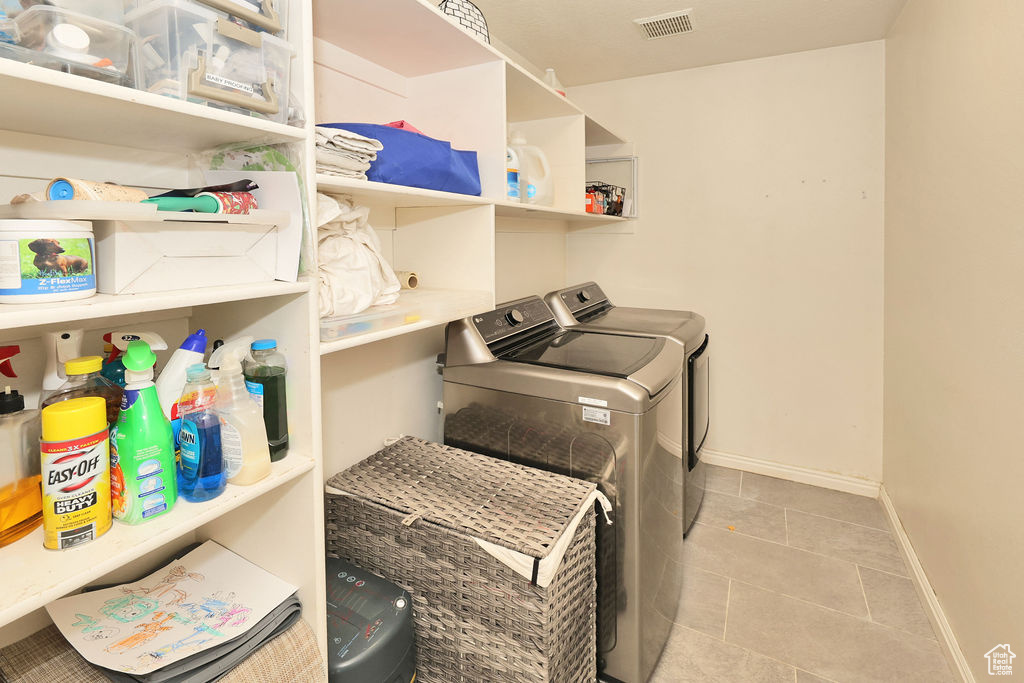 Clothes washing area featuring tile patterned floors, laundry area, visible vents, independent washer and dryer, and baseboards