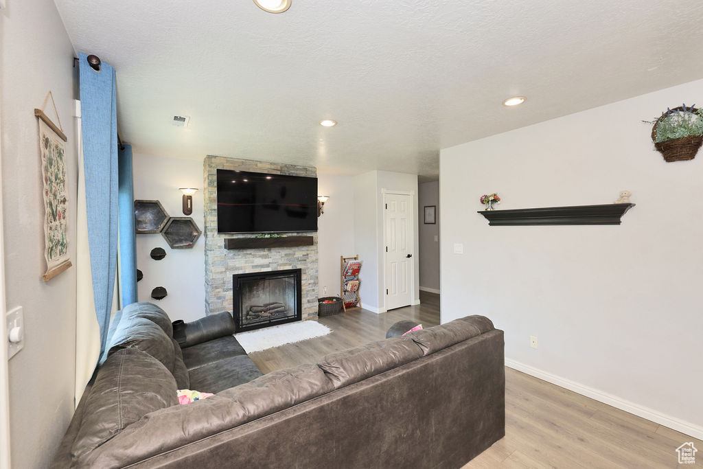 Living room featuring a fireplace, wood finished floors, baseboards, and recessed lighting