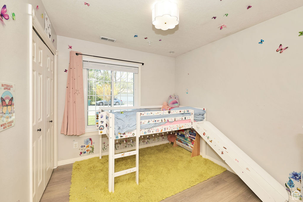 Bedroom featuring baseboards, wood finished floors, visible vents, and a closet