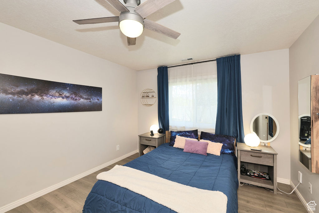 Bedroom with visible vents, baseboards, a ceiling fan, and wood finished floors