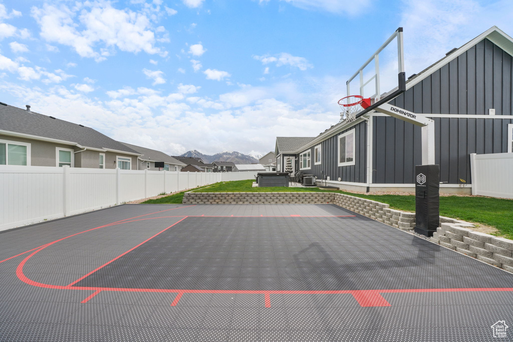 View of sport court with a residential view, fence, and basketball hoop