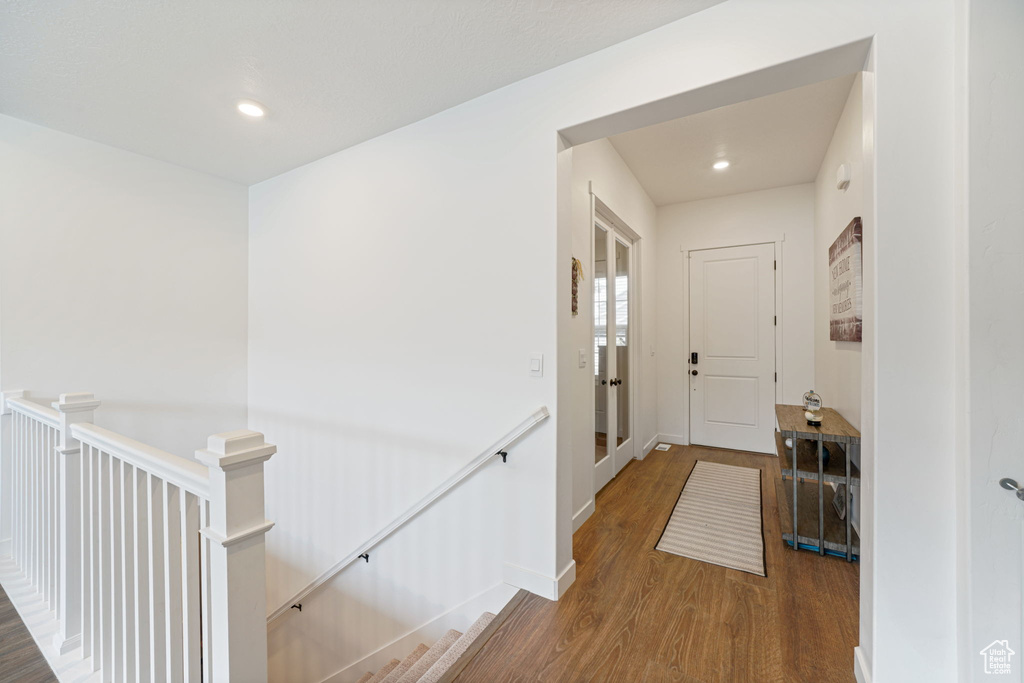 Hallway featuring recessed lighting, baseboards, wood finished floors, and an upstairs landing