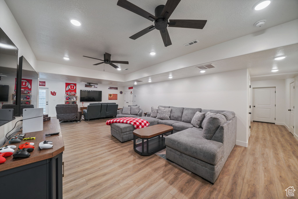 Living area featuring light wood-style floors, ceiling fan, and visible vents