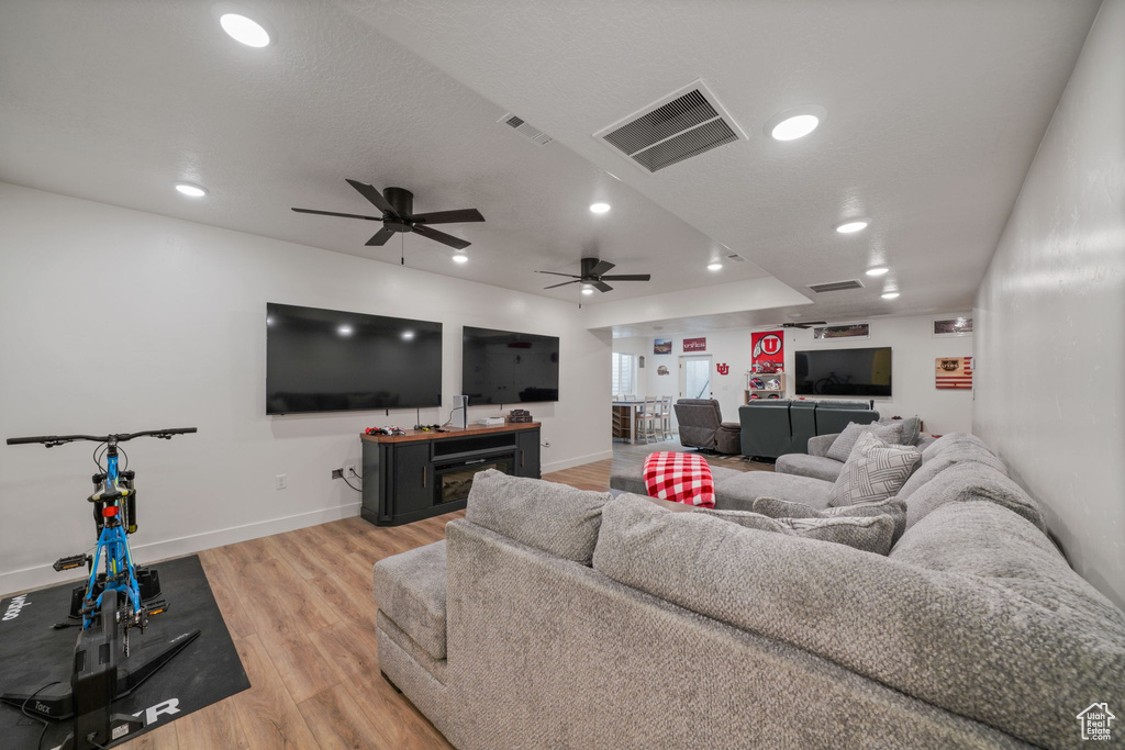 Living room featuring ceiling fan, visible vents, and light wood finished floors