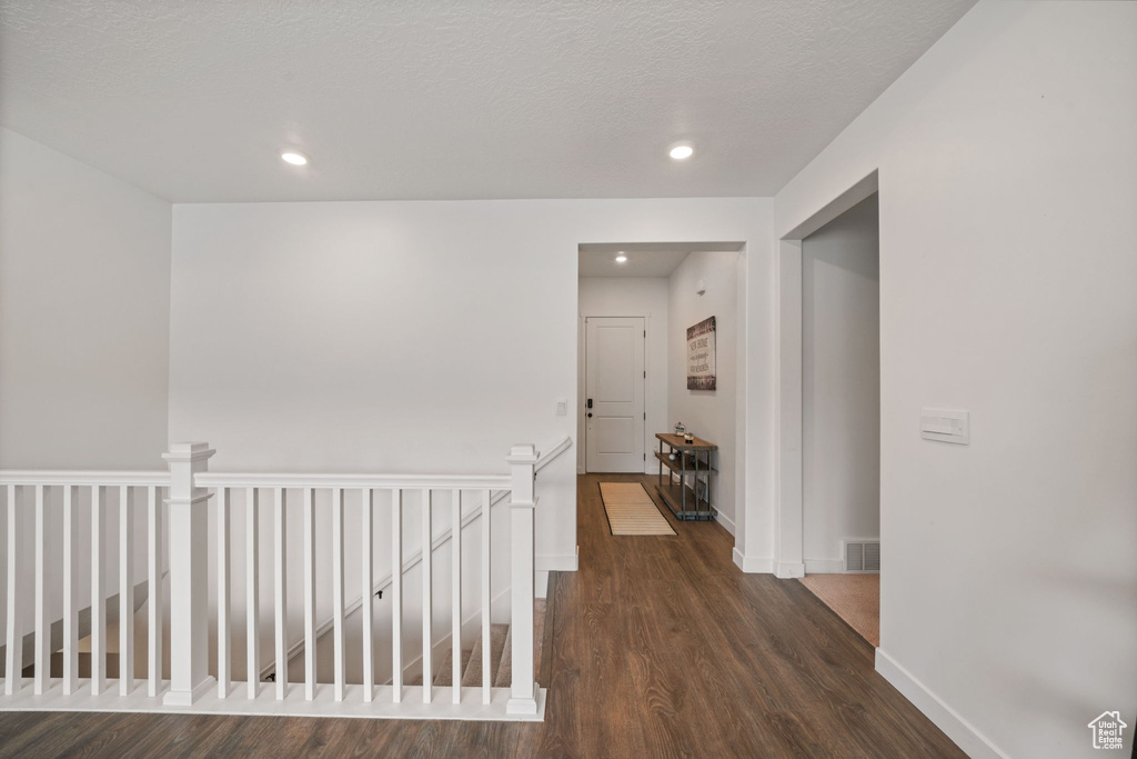 Hallway featuring recessed lighting, baseboards, an upstairs landing, wood finished floors, and visible vents