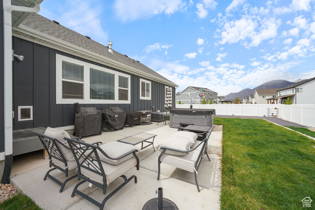View of patio with grilling area, a residential view, a hot tub, fence, and an outdoor hangout area