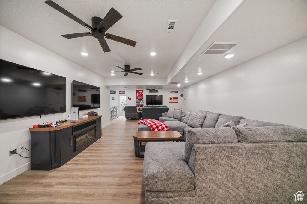 Living area with baseboards, a ceiling fan, visible vents, and light wood-type flooring