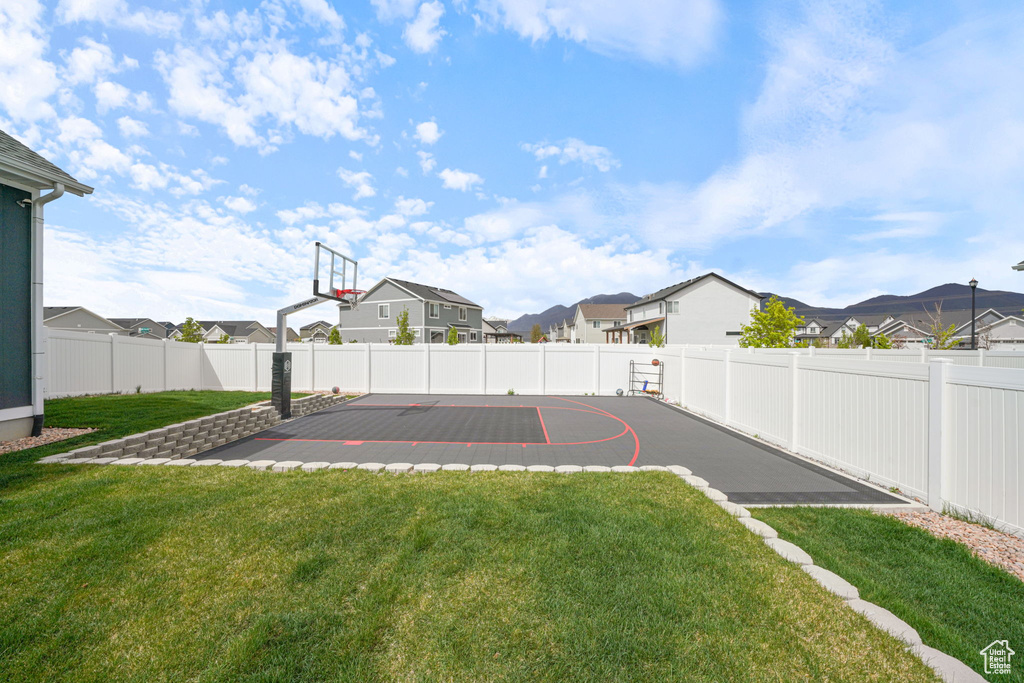 View of basketball court with a lawn, a fenced backyard, a residential view, and basketball court