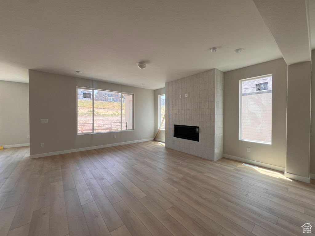Unfurnished living room featuring light wood-style flooring, healthy amount of natural light, and a fireplace
