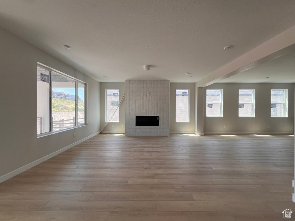 Unfurnished living room with light wood finished floors and a large fireplace