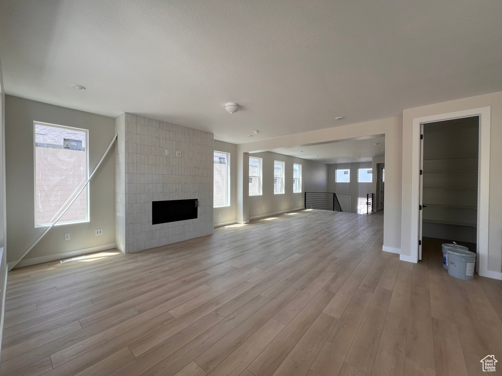 Unfurnished living room featuring light wood-type flooring and a fireplace
