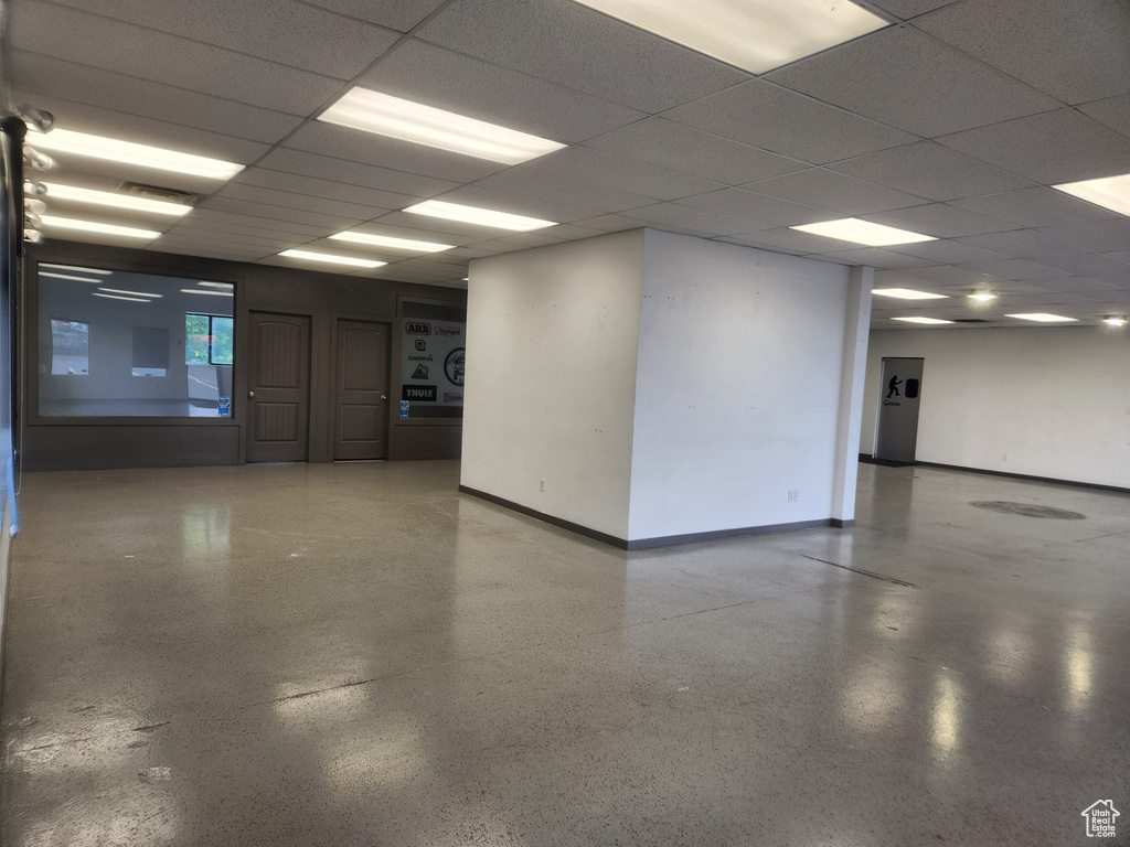 Empty room featuring speckled floor and a drop ceiling