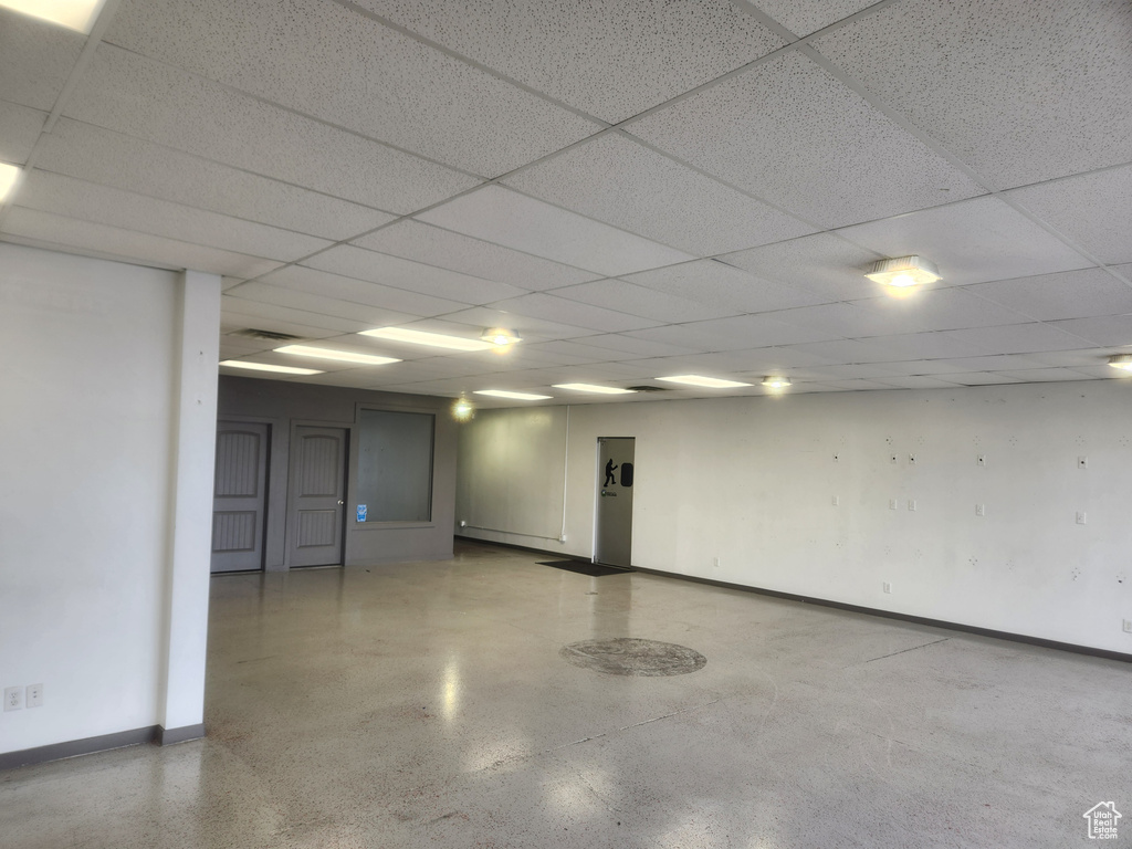 Empty room featuring speckle patterned floor and a paneled ceiling