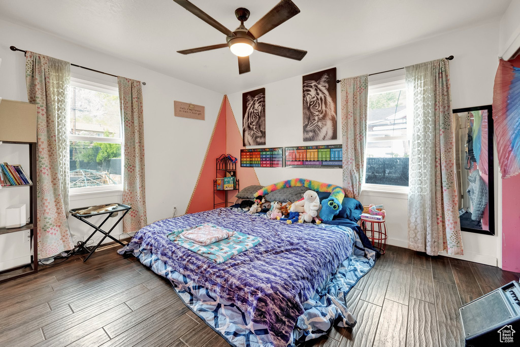 Bedroom featuring a ceiling fan, multiple windows, and wood finished floors