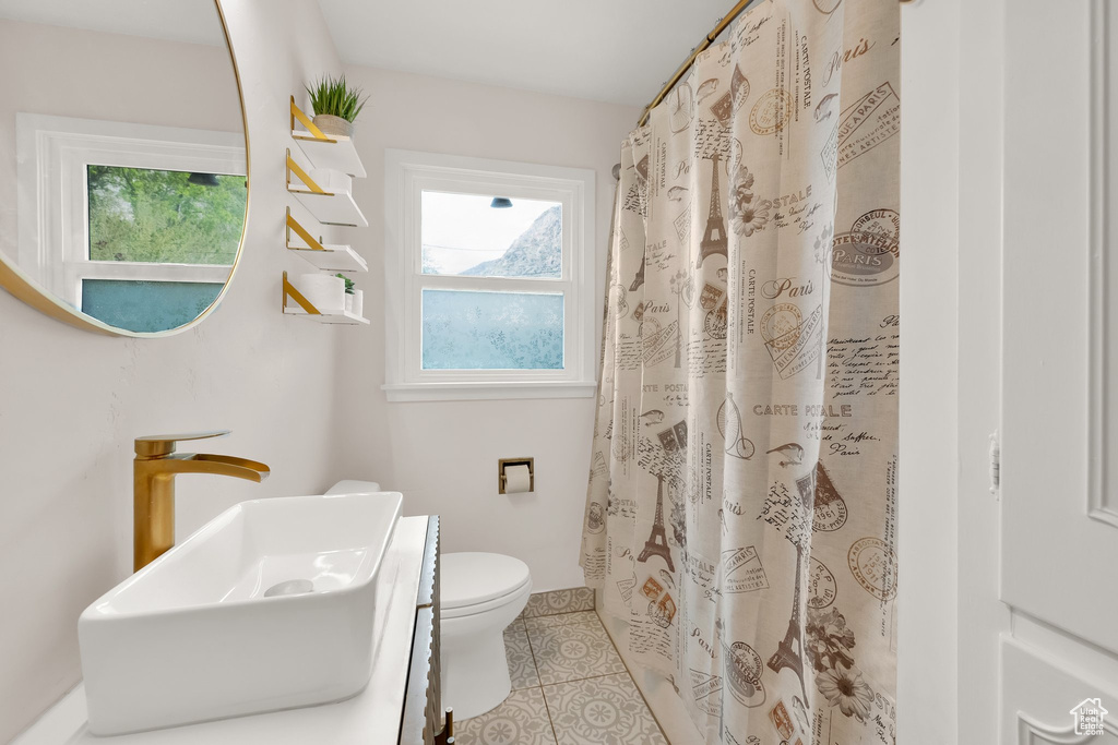Bathroom with tile patterned floors, baseboards, vanity, toilet, and a shower with shower curtain