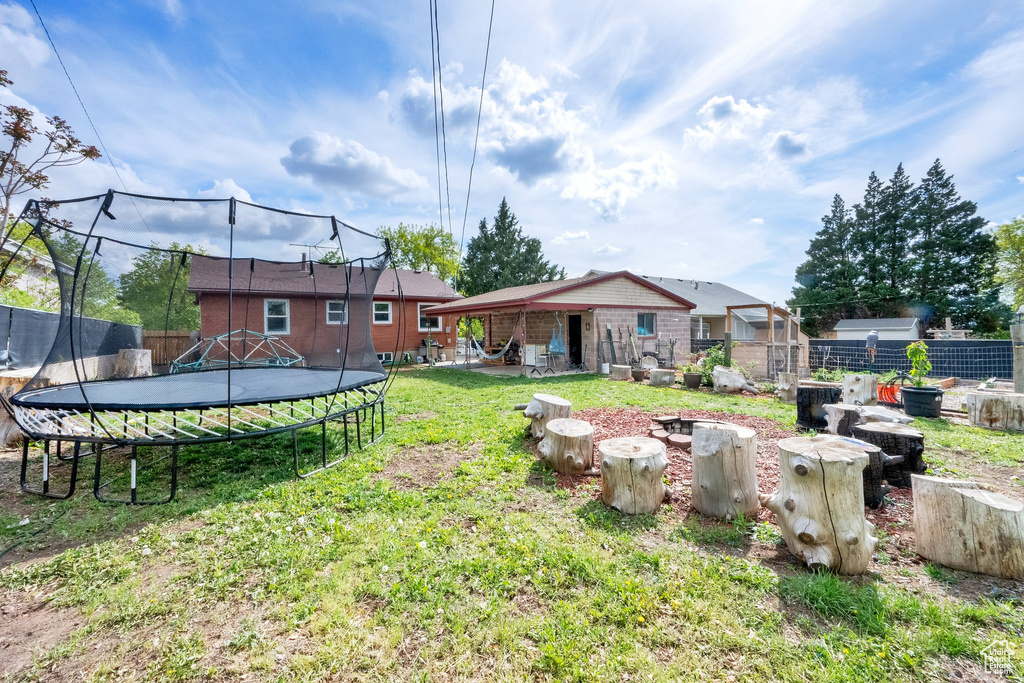 View of yard featuring an outdoor structure, a trampoline, and fence