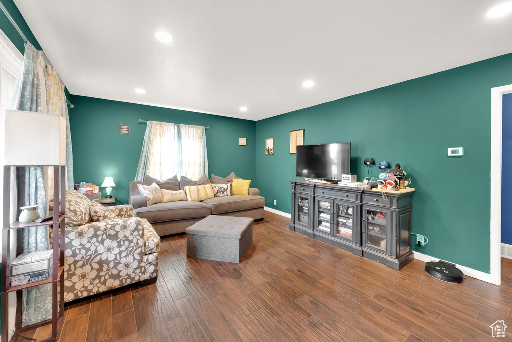 Living room featuring recessed lighting, baseboards, wood finished floors, and an accent wall