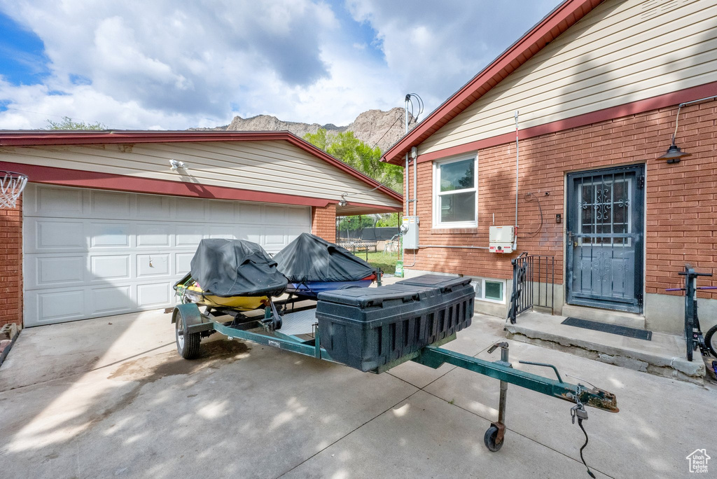 View of patio / terrace with a garage, an outbuilding, concrete driveway, and a mountain view