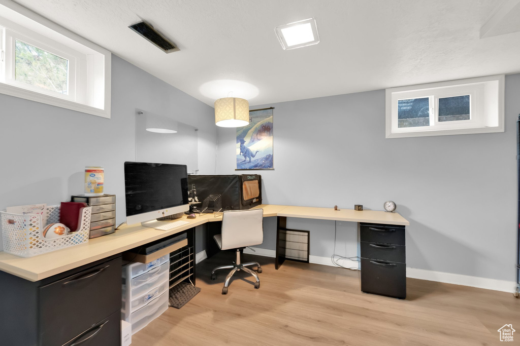 Office area with visible vents, light wood-style flooring, and baseboards