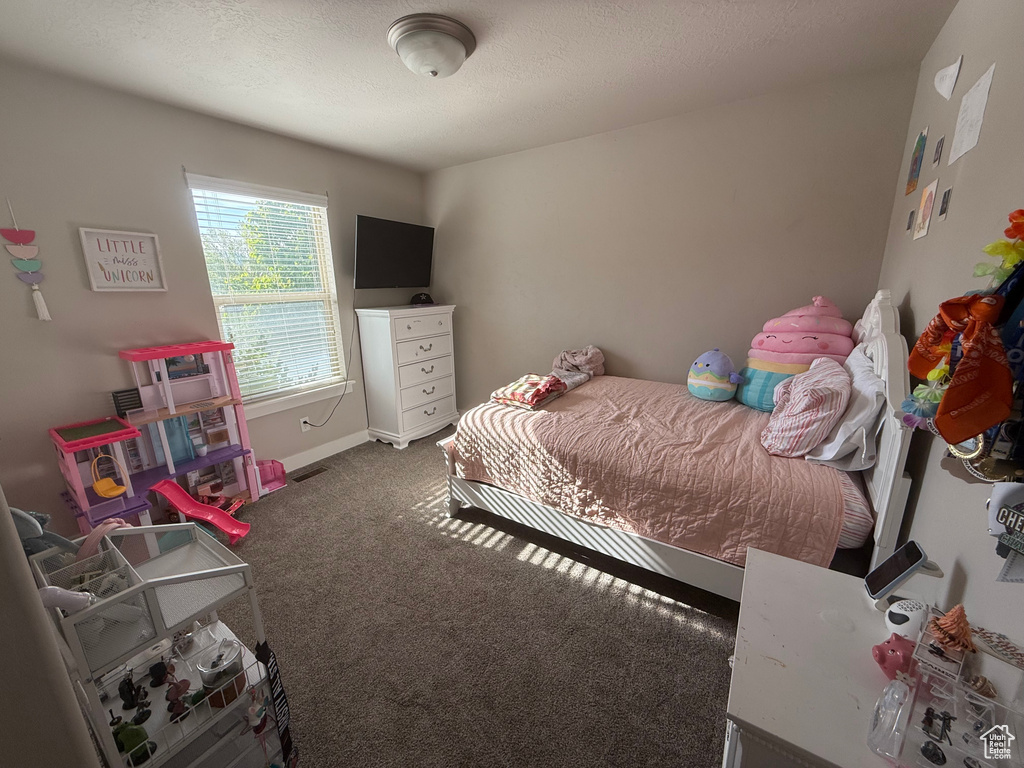 Bedroom featuring a textured ceiling, baseboards, and carpet