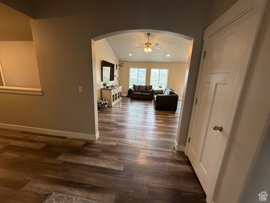 Corridor featuring arched walkways, dark wood-style flooring, baseboards, and recessed lighting