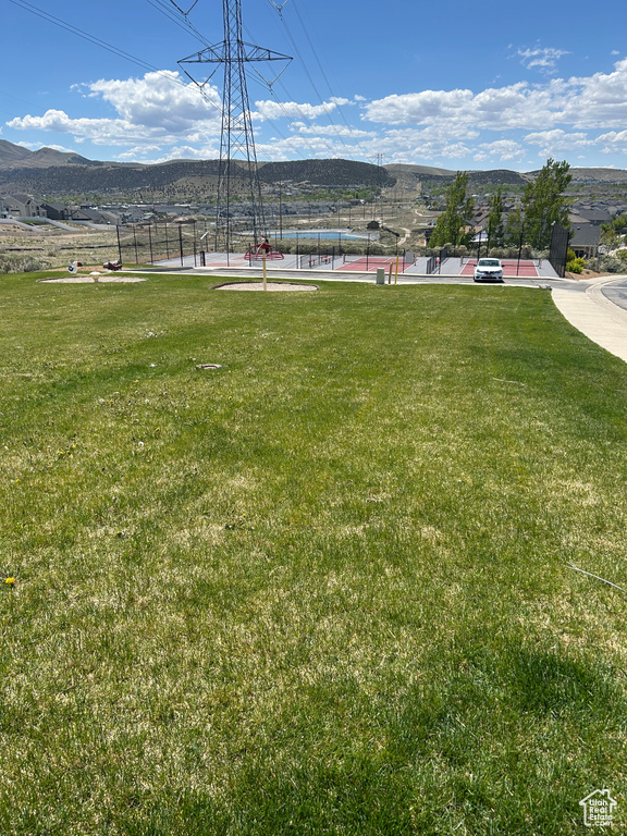 View of yard with a tennis court, a mountain view, and fence