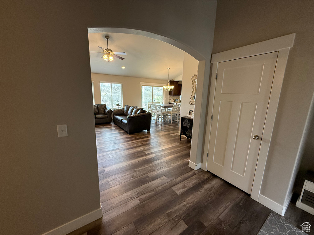 Hallway with arched walkways, baseboards, dark wood-style flooring, and a chandelier