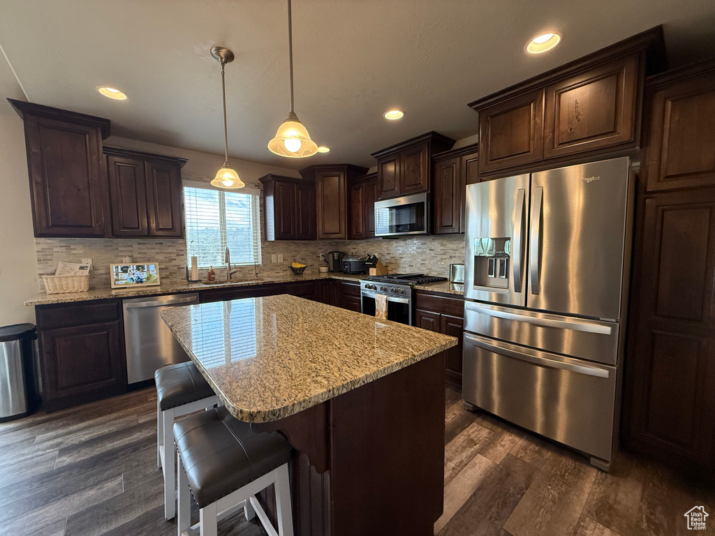 Kitchen with stainless steel appliances, a sink, dark brown cabinets, dark wood-style floors, and recessed lighting
