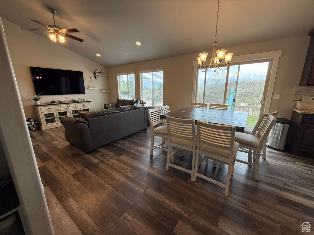 Dining room with dark wood finished floors, lofted ceiling, recessed lighting, ceiling fan, and a chandelier